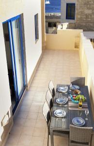 una mesa con sillas y platos de comida. en Ir-Rixa Holiday Penthouse en Għajnsielem