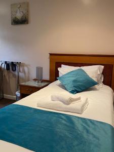 a bed with a blue pillow and towels on it at The Whistle and Flute in Barnetby le Wold