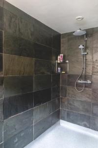 a bathroom with a shower with black tiles at The Costrel in Tenbury