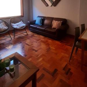 un salon avec un canapé en cuir et une table dans l'établissement Apto Tranquilo e Aconchegante no Centro de Águas de Lindoia, à Águas de Lindóia