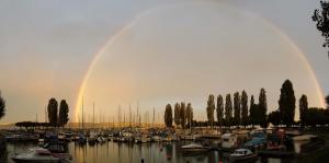 Ein Regenbogen über einem Haufen Boote in einem Jachthafen. in der Unterkunft Ferienwohnung und Pension Antje Ekert in Uhldingen-Mühlhofen