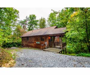 a log cabin in the woods with a driveway at Peekaboo with Hot Tub, Pool Table, and Jacuzzi in Pigeon Forge