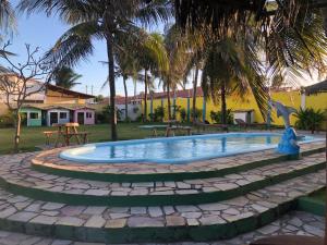 a swimming pool in a yard with palm trees at Pousada Sol e Mar Buzios RN in Nísia Floresta