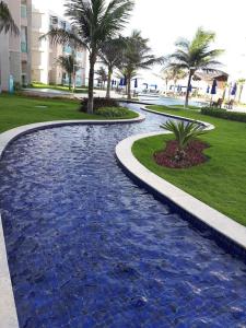 een zwembad van blauw water met palmbomen in een park bij Riviera Beach Place - Aquiraz Riviera in Fortaleza