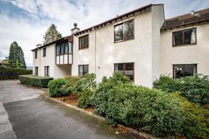 a white building with bushes in front of it at Bellman apartment - Pet friendly with parking - FREE off-site Health Club access with Pool, Sauna, Steam Room & Gym Short 10 Minute Drive Away in Winster