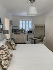 1 dormitorio con 1 cama blanca grande y escritorio en Harford en-suite Rooms, en Lymington