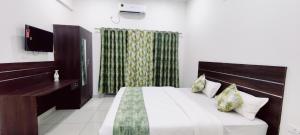 een slaapkamer met een bed, een bureau en een televisie bij Suvarna Elite - Premium Apartment Hotel in Mysore