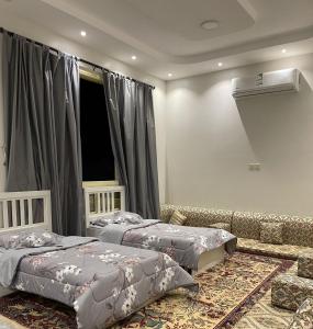 um quarto com 2 camas e um sofá em شاليه العبير em Buraydah