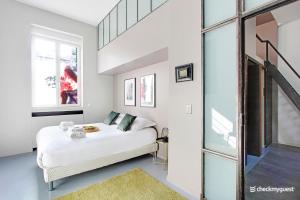 a white bedroom with a bed and a window at Superbe Loft 2BR - Buttes Chaumont in Paris