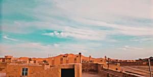 a group of buildings with a cloudy sky in the background at Gite GAMRA in Merzouga