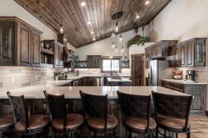 Una cocina con gabinetes de madera y una isla con taburetes de bar. en My Yellowstone Retreat, en Island Park