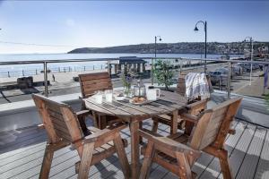 a wooden table and chairs on a deck overlooking the beach at Atlantic View, Penzance in Penzance