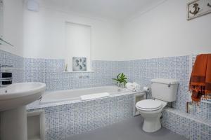 a bathroom with a tub and a toilet and a sink at Atlantic View, Penzance in Penzance
