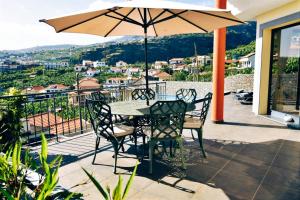 a table and chairs on a balcony with an umbrella at Vila Juntos by Your Madeira Rentals in Ponta do Sol