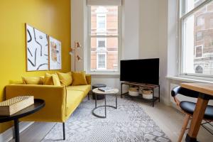 ロンドンにある2VH Virginia House, 31 Bloomsbury Way by City Living Londonのリビングルーム(黄色のソファ、薄型テレビ付)