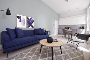 ein Wohnzimmer mit einem blauen Sofa und einem Tisch in der Unterkunft 1VH Virginia House, 31 Bloomsbury Way by City Living London in London