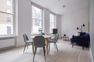 a white living room with a table and chairs at 1VH Virginia House, 31 Bloomsbury Way by City Living London in London