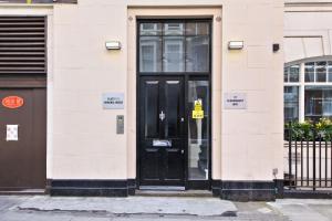une porte noire d'un bâtiment avec un panneau sur celui-ci dans l'établissement 2VH Virginia House, 31 Bloomsbury Way by City Living London, à Londres