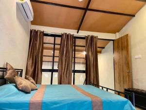 纳加奥恩Enliven Homestay Alibag, Alibaug的带蓝色床和窗户的卧室 更多37张照片