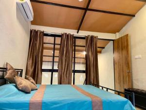 a bedroom with a blue bed and a window at Enliven Homestay Alibag, Alibaug in Nagaon