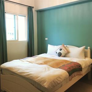 a bedroom with a large bed with a blue wall at Beauty Home Homestay in Hualien City