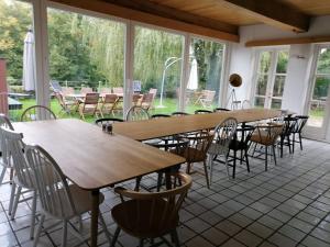un grupo de mesas y sillas en una habitación con ventanas en Das Wewelsflether Bäckerhaus - 250qm für 12 Gäste en Wewelsfleth
