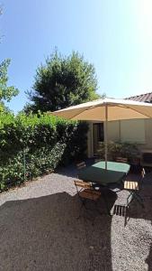 une table avec un parasol et une chaise dans l'établissement T1 cosy climatisé indépendant sur prop privée à Sanguinet - lac, océan, Bassin d'Arcachon, Dune du Pyla, à Sanguinet