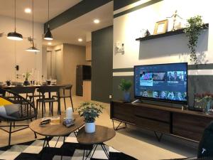 a living room with a large flat screen tv and tables at KL Gateway Premium Residence I HomeBrickz in Kuala Lumpur