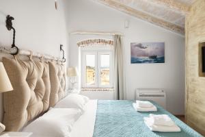 a white bedroom with a large bed with two towels at Sky Loft Corfu Old Town Apartments in Corfu