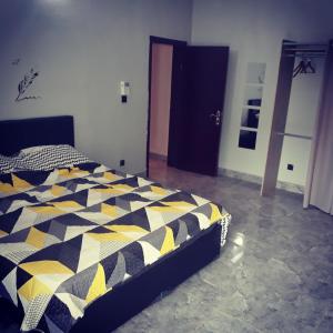 ein Schlafzimmer mit einem Bett mit einer schwarzen und gelben Bettdecke in der Unterkunft RESIDENCE L'ESCALE équipements moderne in Bamako