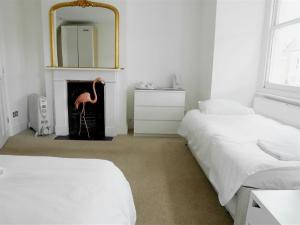 a room with two beds and a fireplace with a flamingo statue at Kew Studios and Rooms in Kew