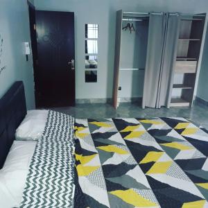 a bedroom with a bed with a checkered blanket at RESIDENCE L'ESCALE équipements moderne in Bamako