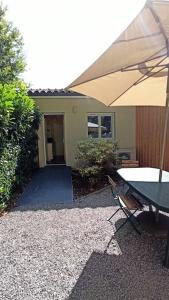 une table et un parasol devant une maison dans l'établissement T1 cosy climatisé indépendant sur prop privée à Sanguinet - lac, océan, Bassin d'Arcachon, Dune du Pyla, à Sanguinet