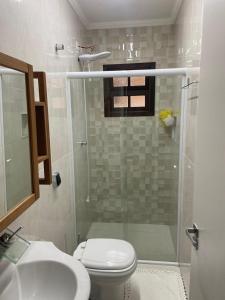 ein Bad mit einer Dusche, einem WC und einem Waschbecken in der Unterkunft casa 300 mts da praia in Juquei