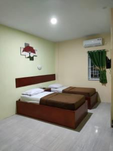 a bedroom with two beds and a television in it at Wisma Cemara Dumai in Dumai +2 photos