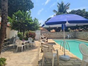 a patio with chairs and an umbrella next to a pool at Hostel Iguabella - RJ in Iguaba Grande