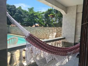 a hammock on a balcony overlooking a pool at Hostel Iguabella - RJ in Iguaba Grande