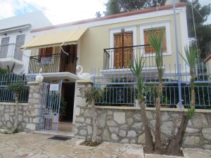 a house with a fence and trees in front of it at Chryssa Rooms in Symi