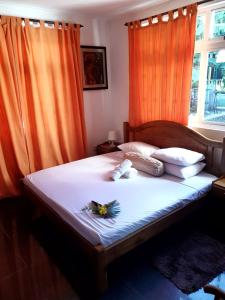 a bedroom with a large bed with orange curtains at Kai Selfcatering in La Digue