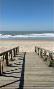 un paseo marítimo de madera que conduce a una playa de arena en Casa de Praia Navegantes - 100 metros do mar en Navegantes