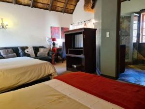 une chambre avec un lit, une télévision et un canapé dans l'établissement Khaya Africa Guesthouse, à Midrand