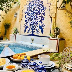 a table with bowls and plates of food next to a pool at Les Bains de Fez Tara in Fez