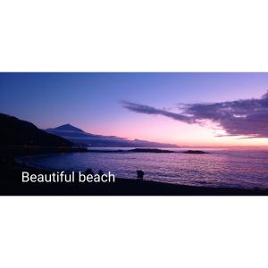 a person standing next to a body of water at sunset at Beautiful beach in Santa Cruz de Tenerife