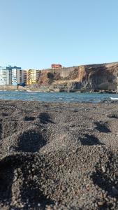 a beach with rocks and the water and buildings at Beautiful beach in Santa Cruz de Tenerife