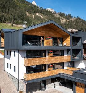 una casa con tetto nero e ponti in legno di Hotel Ladinia Dolomites View a Pozza di Fassa