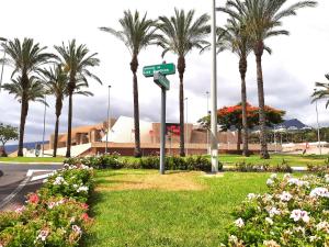 ein Straßenschild in einem Park mit Palmen und Blumen in der Unterkunft Perfectly located apartment with pool in Playa de las Americas
