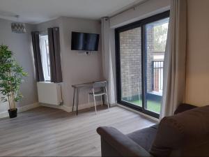 uma sala de estar com um sofá, uma mesa e uma janela em Apartments Heathrow - Hounslow em Cranford