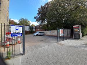 a parking lot with a gate with a car in it at Apartments Heathrow - Hounslow in Cranford