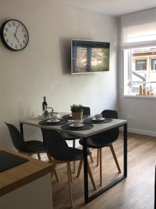 a dining room table with chairs and a clock on the wall at Apartament Impresja II in Rowy