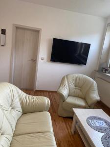 sala de estar con 2 sillas y TV de pantalla plana en familienfreundliche Ferienwohnung Tina, en Rollshausen